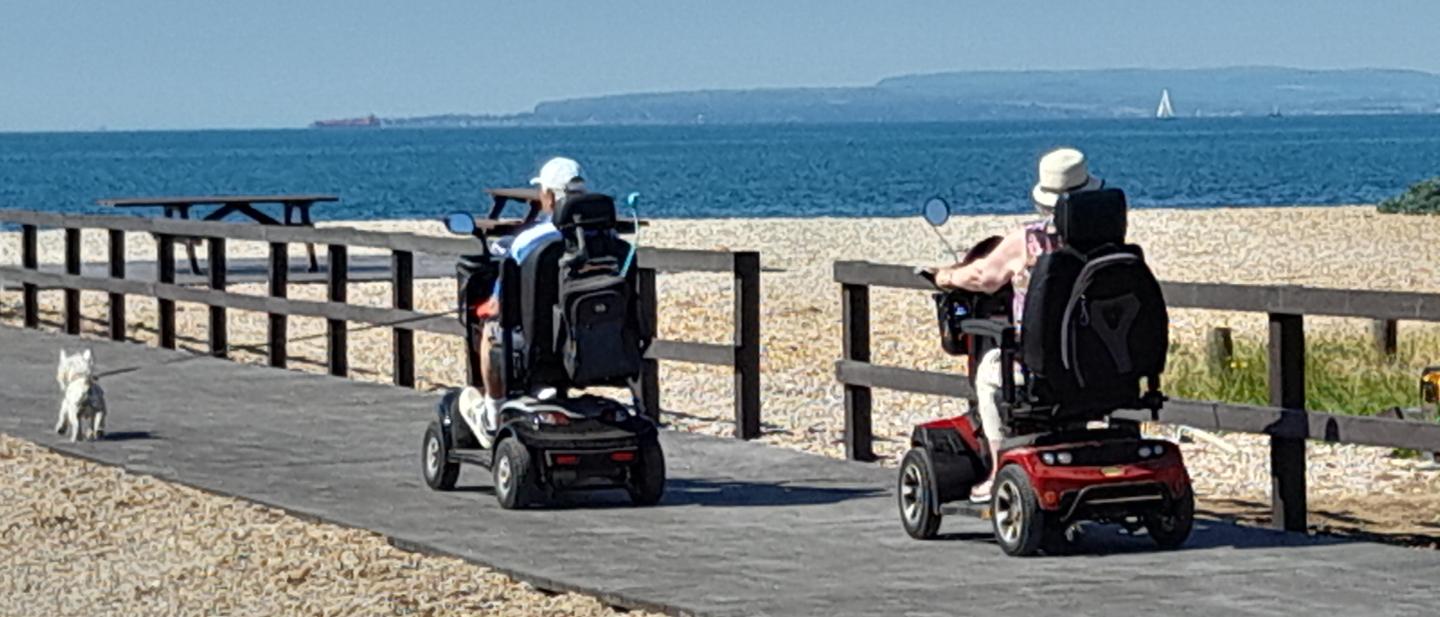 Two people in mobility scooters using the boardwalk